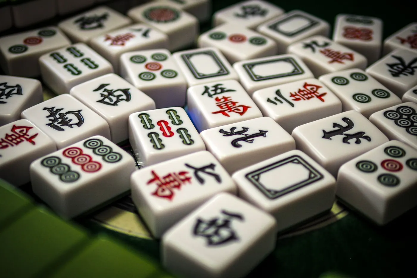 Mahjong tiles with red and green characters on a green table